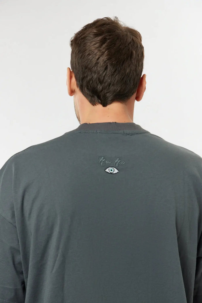 Back of a man wearing a grey Cotton T-Shirt with a small eye graphic and text below the collar
