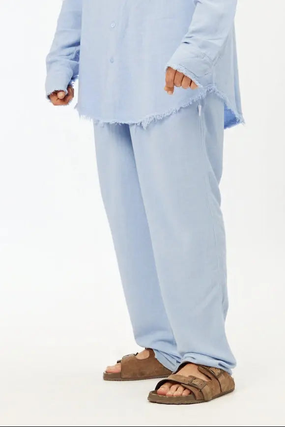 Person wearing a light blue outfit with brown sandals on a white background