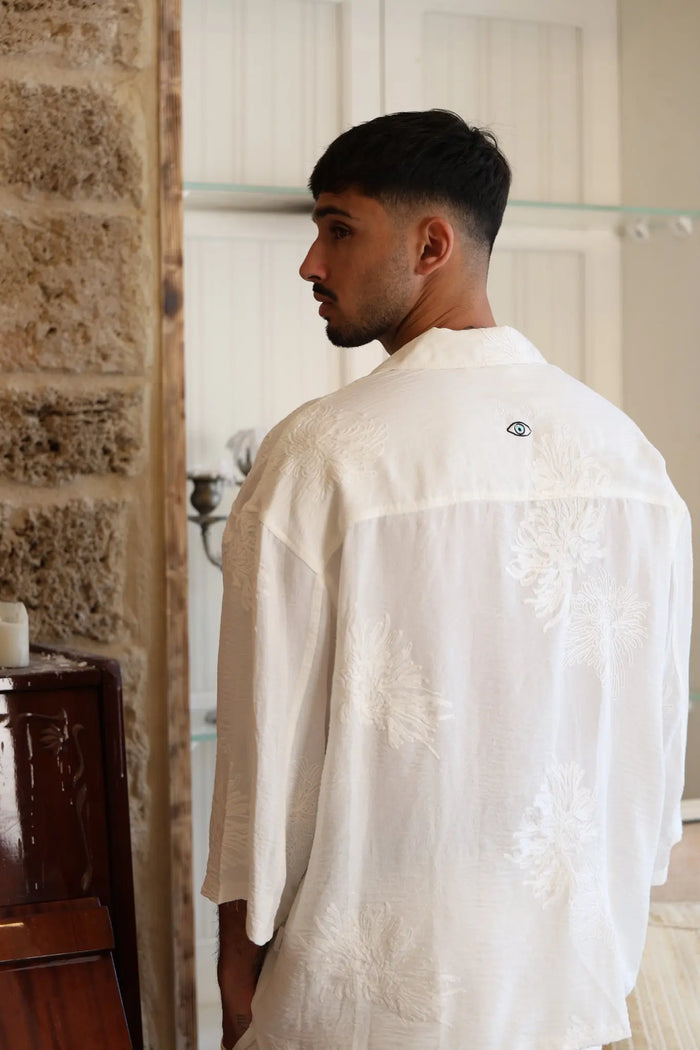 Man wearing a white SPARKS 3/4 Sleeve Button-Up Shirt with embroidered floral patterns and an eye logo on the back