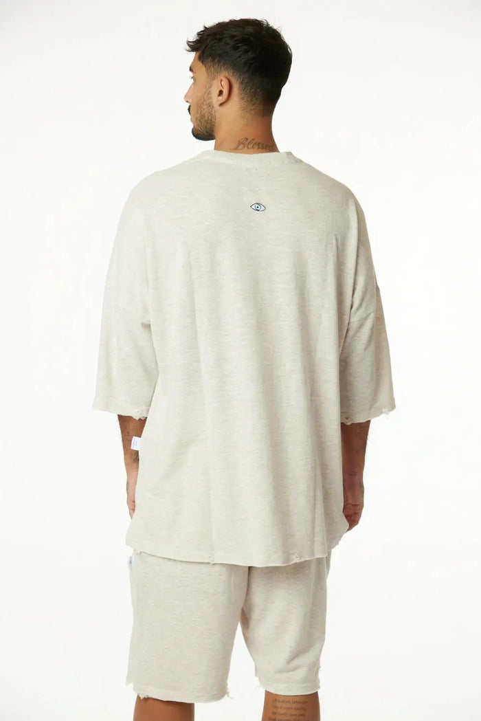 Man from behind wearing a 3/4 Sleeve Nicki Soft in Melange Stone with a small eye graphic on the back