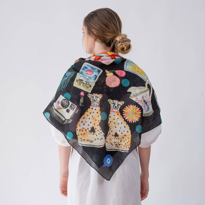 Woman wearing a colorful scarf with cat designs on a white background