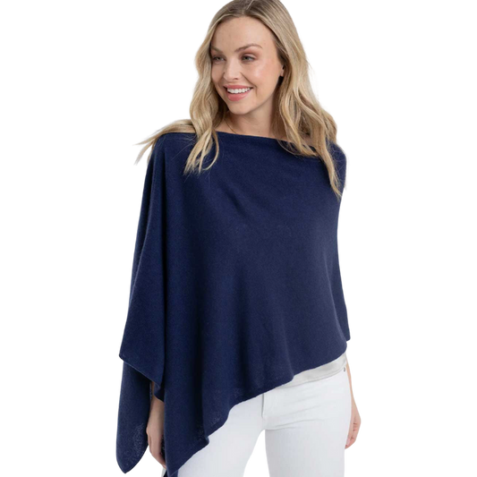 Woman wearing a navy blue poncho over a white outfit on a white background
