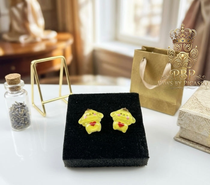 Yellow earrings on a black display box with a decorative background