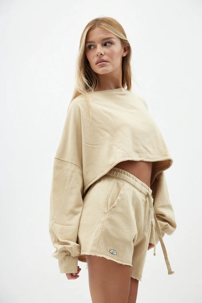 Woman wearing a beige sweatshirt and shorts set on a white background