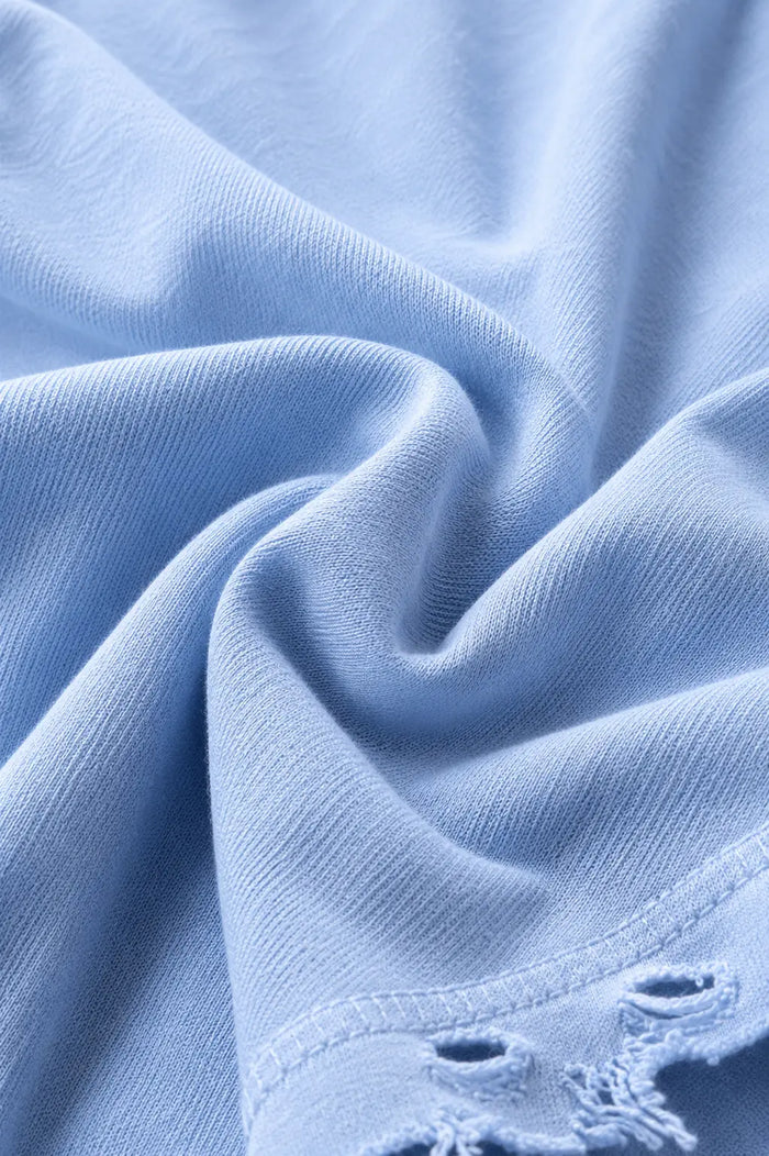 Close up of light blue Dor Oversized Shirt fabric with visible texture and distressed hem