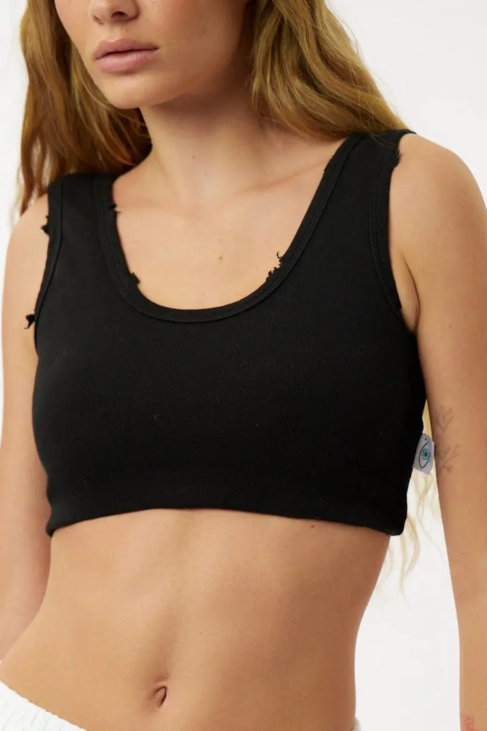 Black crop top worn by a person on a plain background