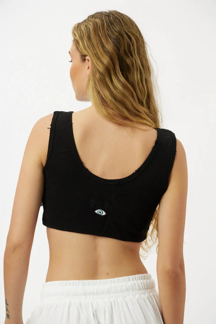 Back of a woman wearing an Essential Crop Top in black with an eye graphic