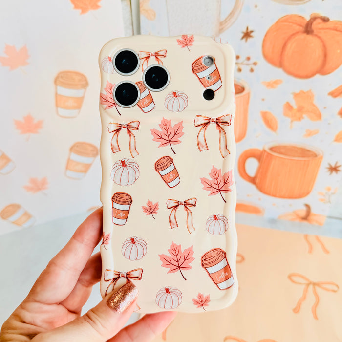 Hand holding the Falling in Love a Latte Wavy Luxe MagSafe iPhone case, showing the cream print with coffee cups, pumpkins, maple leaves and rust bows.