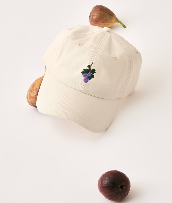 Beige cap with a fig design surrounded by figs on a light background