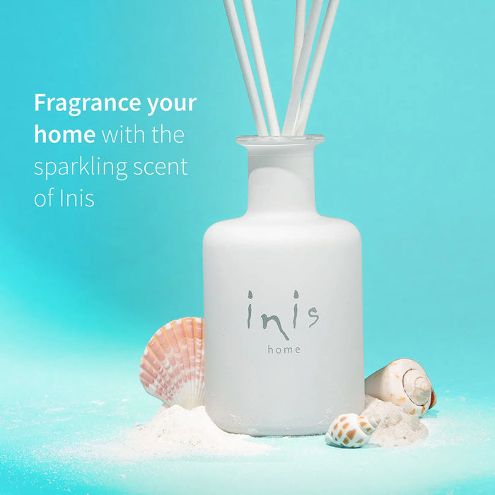 White diffuser bottle with 'inis' branding on a blue background with seashells.