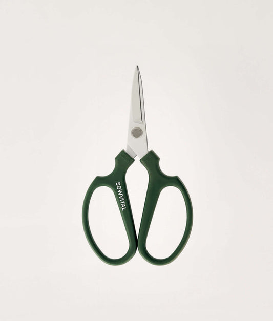 Green-handled scissors on a light gray background.