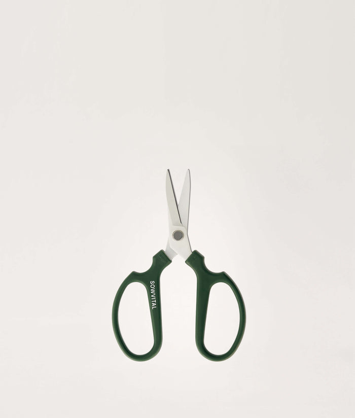 Pair of green-handled scissors on a light gray background.