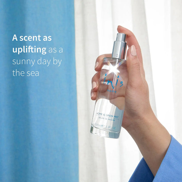 Hand holding a bottle of 'inis' product with a scenic background