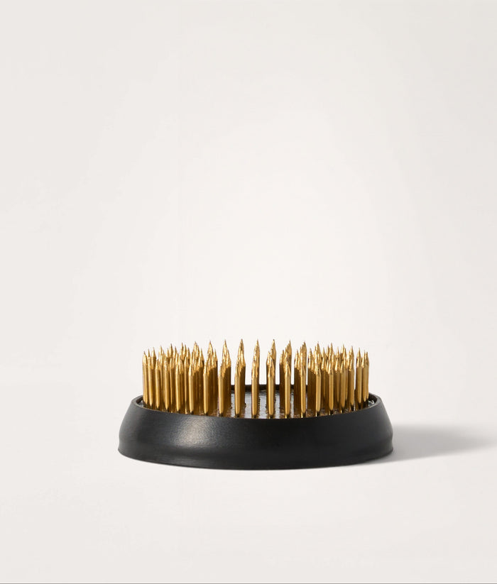 Kenzan with brass pins on a white background.