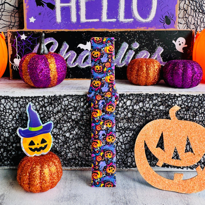 Single Jack-O-Lantern Jive Samsung Galaxy Watch band strap standing beside a jack-o-lantern wearing a purple witch hat.