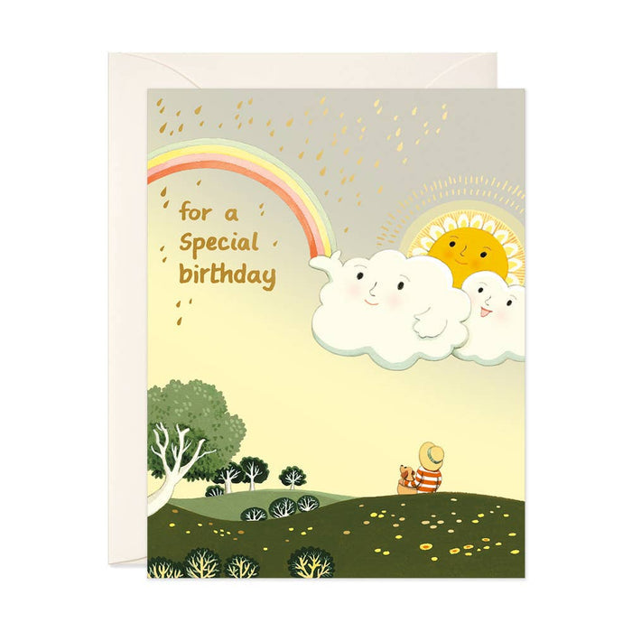Children's birthday card with a rainbow, clouds, and a bear in a field.