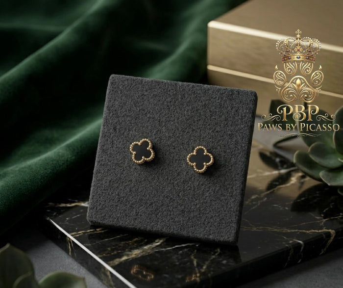 Gold clover-shaped earrings on a black display stand with 'Paws by Picasso' branding.