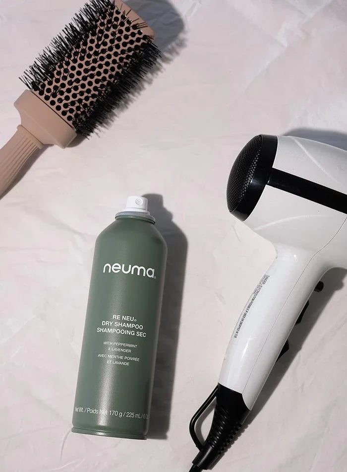 Neuma dry shampoo bottle with a hairbrush and hair dryer on a light background - Hair Care Canada
