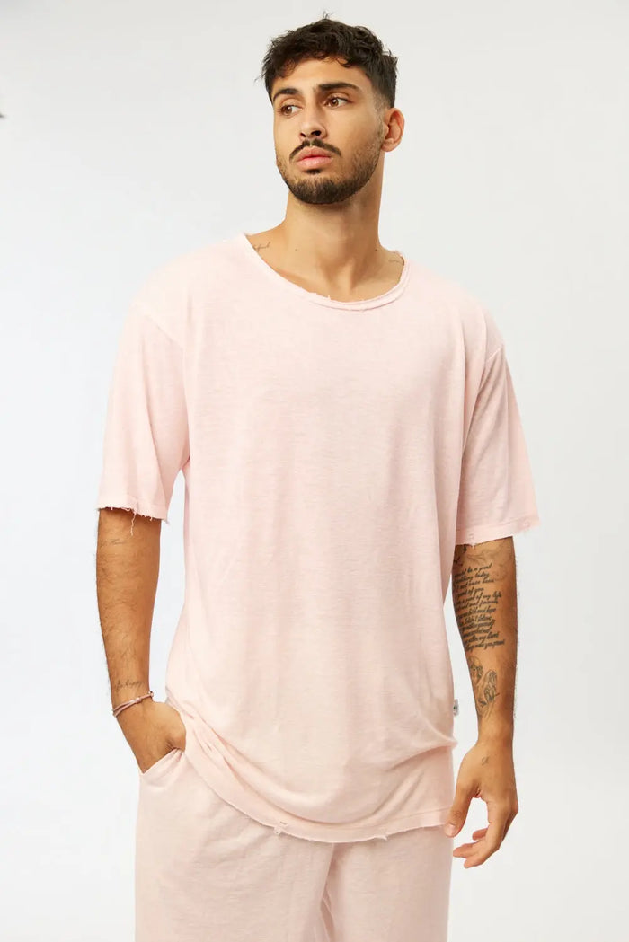 Man wearing a Nicki Soft Open Top in pink, with a relaxed fit and distressed edges