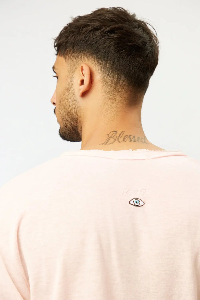 Back of a man wearing a Nicki Soft Open Top in pink, with a small eye graphic and Blessed tattoo on his neck