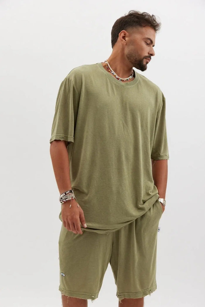 Man wearing TFU Soft Essential Tee in olive with matching shorts, beaded necklaces, and bracelets
