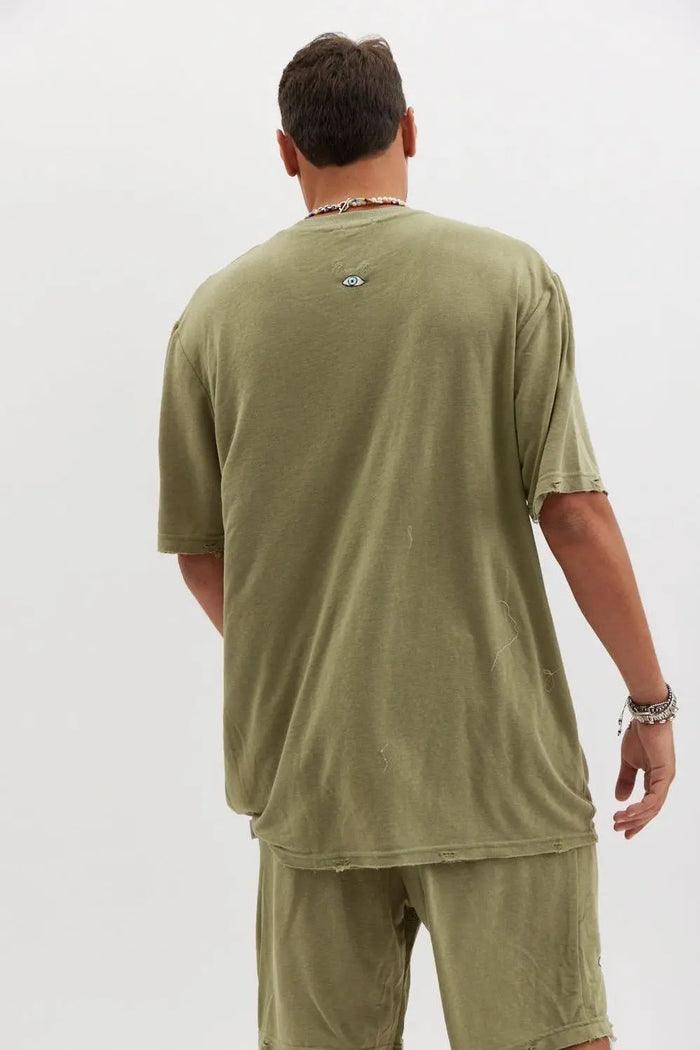 Back of a person wearing an olive TFU Soft Essential Tee and matching shorts, with a small eye graphic on the upper back of the tee