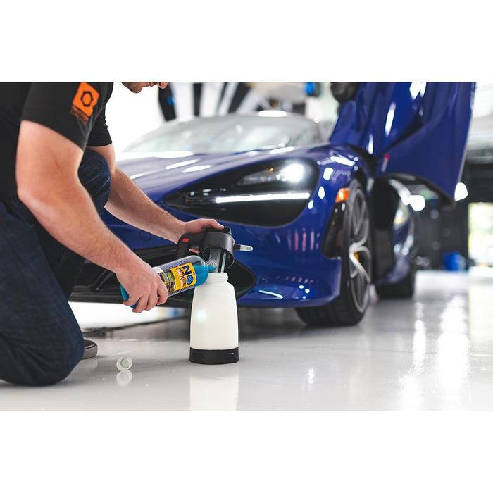 A person pouring Optimum No shine into an IK Sprayer with a blue sports car in the background.