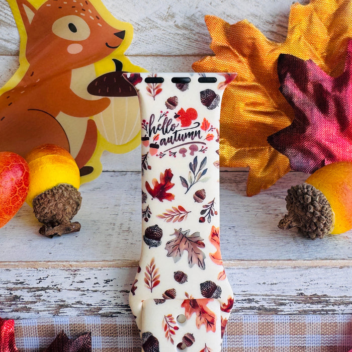 Close-up of the Nutty For Fall Apple Watch band showing the hand-lettered hello autumn script and the watercolor detail on each acorn cap.