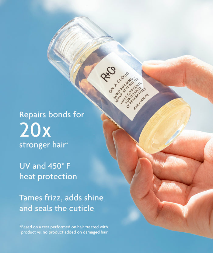 R+Co hair product bottle held by a hand with promotional text on a blue background