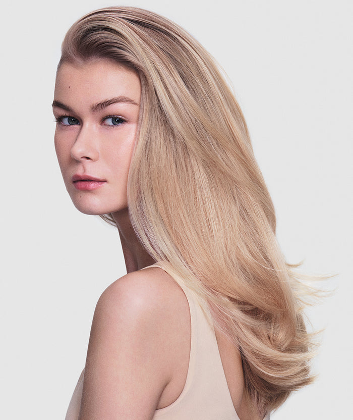 Woman with long, straight blonde hair on a plain background