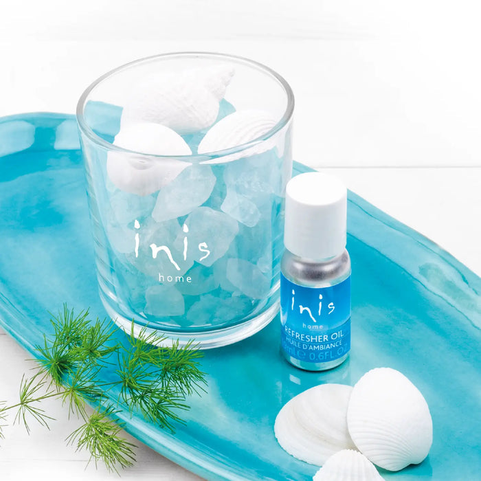 Inis home product with a clear glass, bottle, and decorative elements on a blue tray