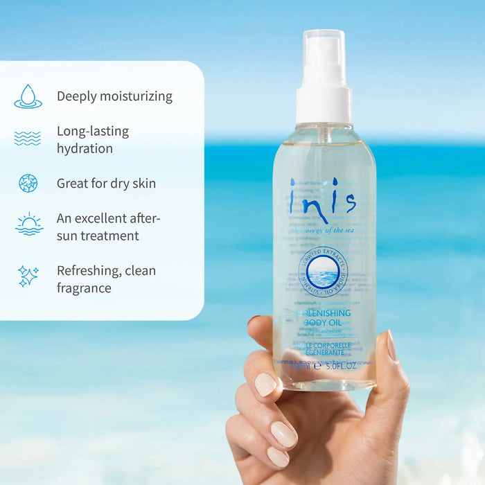 A clear bottle of 'inis' body oil held by a hand with a blue gradient background