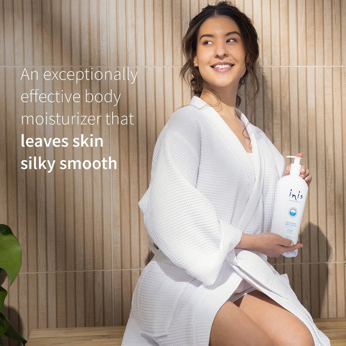 Woman in a white robe holding a bottle of Inis moisturizer with text