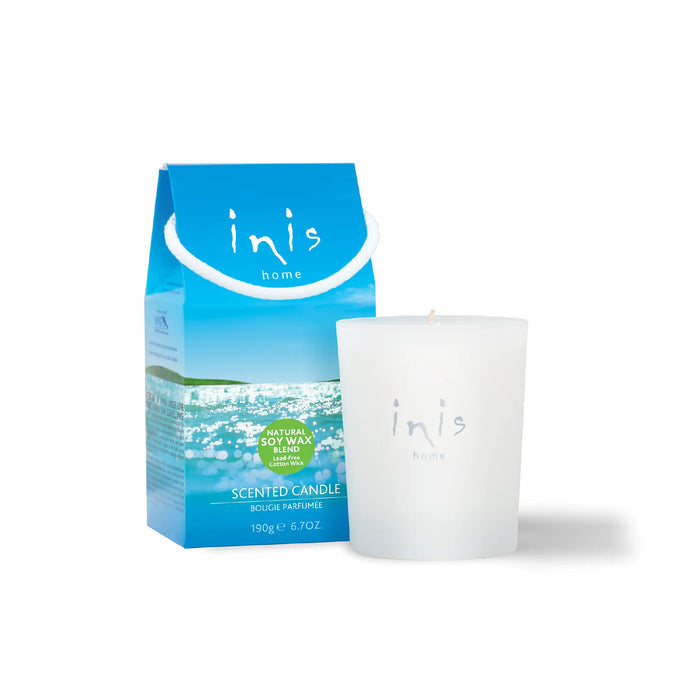 White scented candle and blue packaging with 'inis' branding on a white background