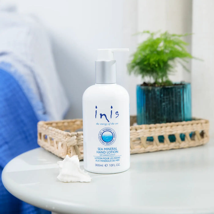 Inis Sea Mineral Hand Lotion bottle on a table with a plant in the background