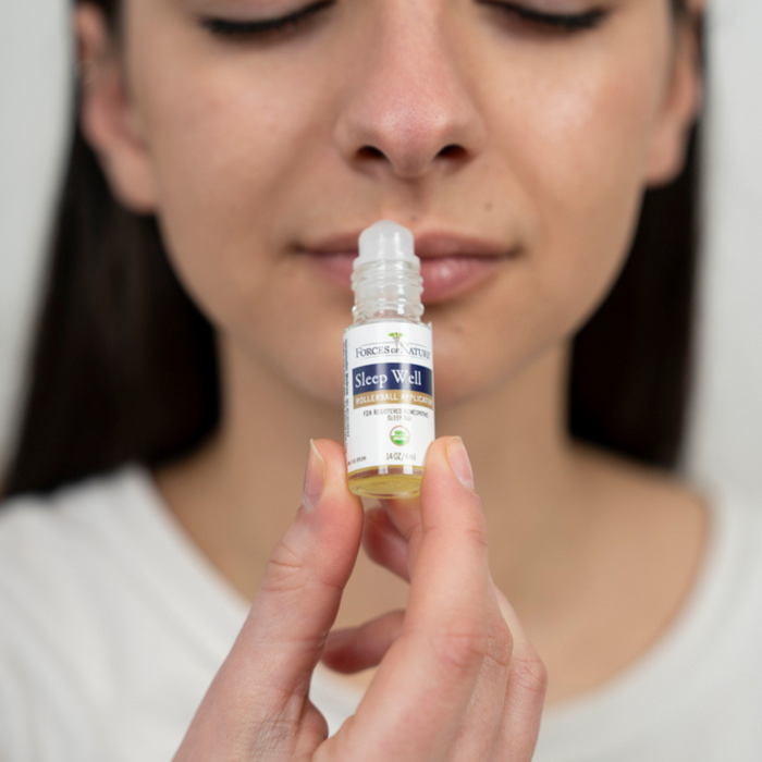 Woman holding Sleep Well roll-on near her nose in a close-up to demonstrate topical sleep support