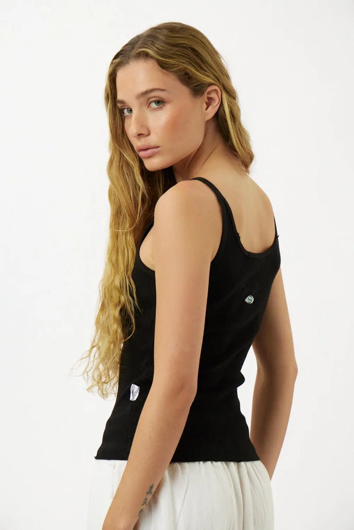 Slim Cotton Tank Top in black, worn by a woman with long blonde hair, looking over her shoulder