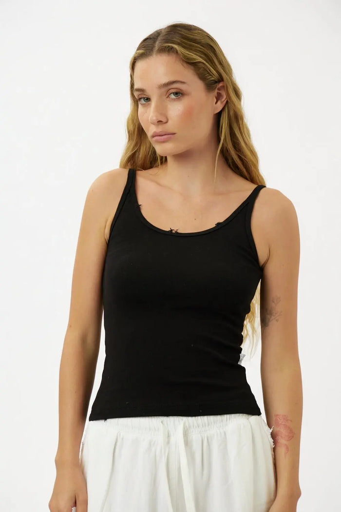 Slim Cotton Tank Top in black worn by a woman with long blonde hair and white pants
