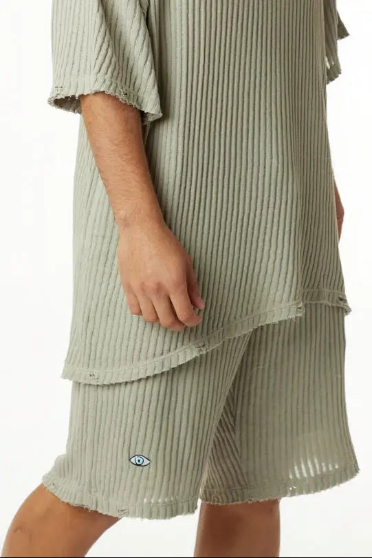 Khaki striped knit pants with an eye graphic on the left leg