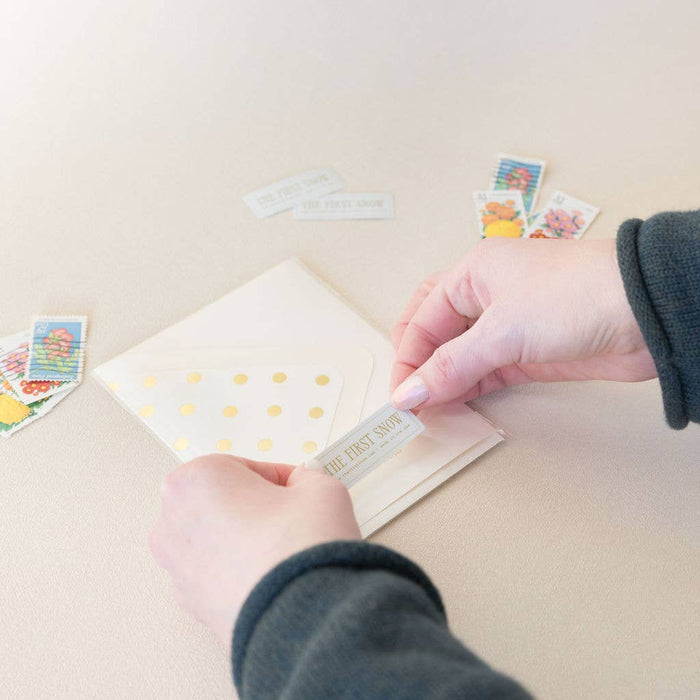 Person applying a gold sticker to a card with other cards in the background
