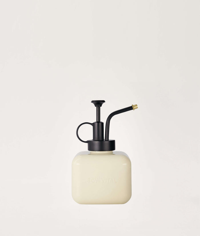 Beige mister with black metal nozzle on a light beige background.