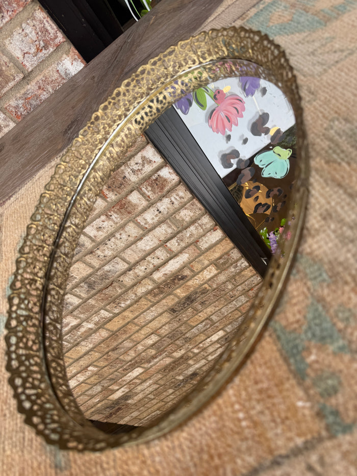 Decorative round mirror with floral design on a textured surface
